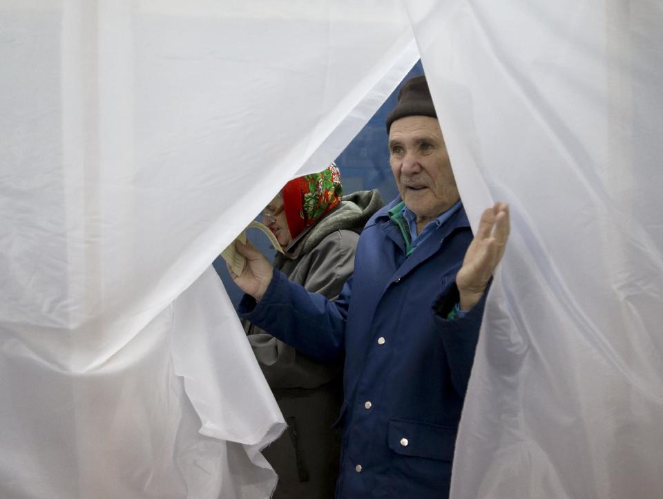 An elderly man exits a voting cabin after casting a vote in the Crimean referendum in Simferopol, Ukraine, Sunday, March 16, 2014. Residents of Ukraine's Crimea region are voting in a contentious referendum on whether to split off and seek annexation by Russia. (AP Photo/Vadim Ghirda)