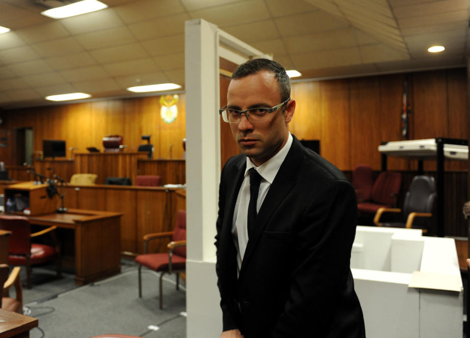 CORRECTS DATES - In this photo taken Friday March 28, 2014, after a postponement was announced, Oscar Pistorius walks past the exhibited door, directly behind him, in court, through which he shot and killed his girlfriend Reeva Steenkamp on St Valentine's Day in 2013. On Tuesday April 8, 2014 Pistroius removed his prosthetics during his testimony and described the moments he fired the shots, that killed Steenkamp. (AP Photo/Werner Beukes, Pool)