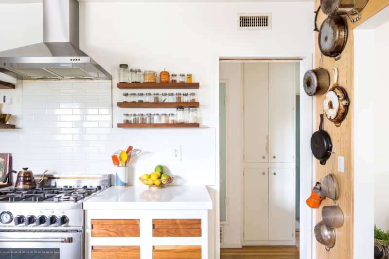 A white and wood farmhouse kitchen with pans hanging on hooks on the wall