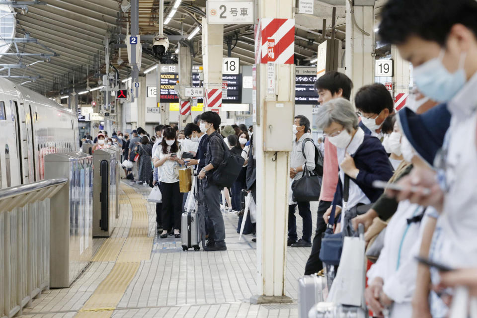 Passengers wait for a bullet train at Tokyo station Friday, June 19, 2020. All domestic restrictions were removed Friday and people can now start travel anywhere in Japan. (Kyodo News via AP)