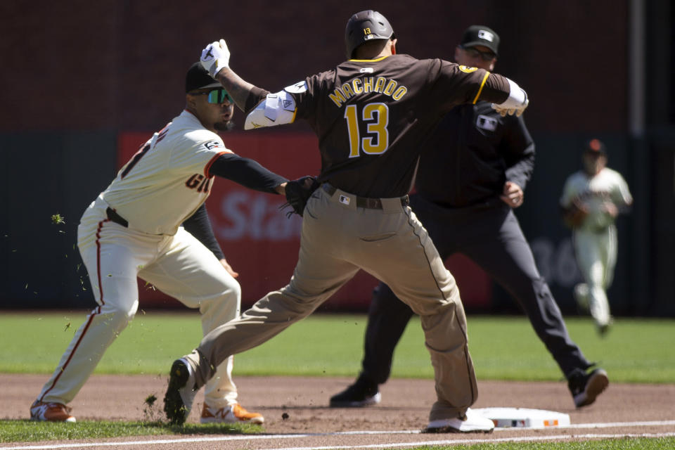 San Francisco Giants first baseman LaMonte Wade Jr., left, puts the tag on San Diego Padres designated hitter Manny Machado (13) on a ground ball during the first inning of a baseball game, Sunday, April 7, 2024, in San Francisco. (AP Photo/D. Ross Cameron)