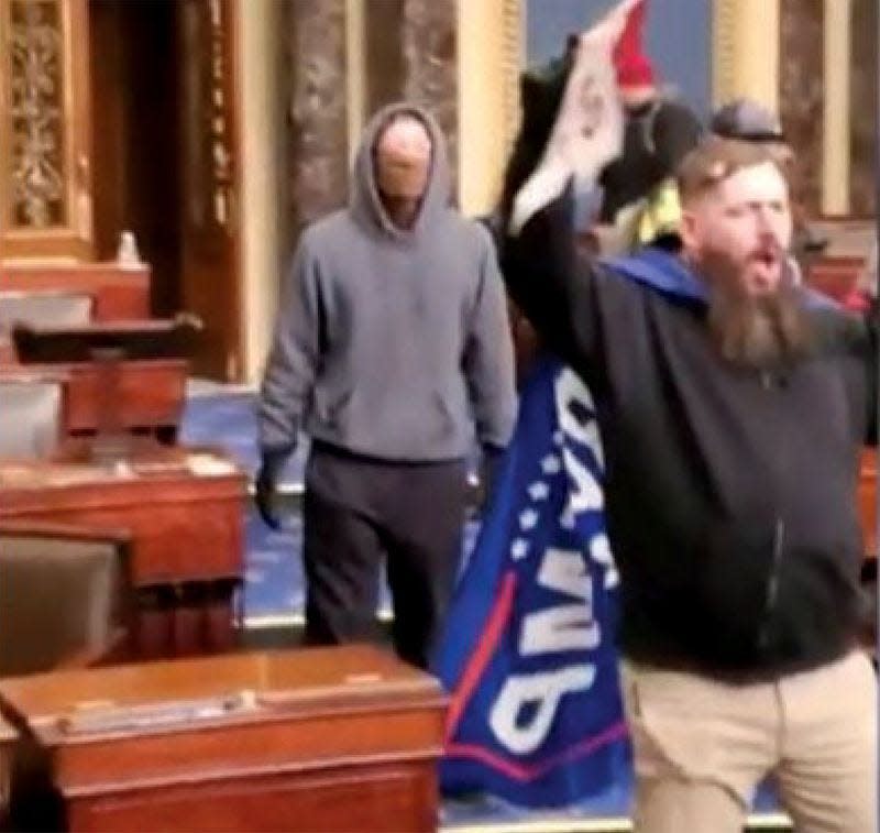 Thomas Adams Jr., of Springfield, right, holds a Trump flag inside the Senate chamber during the Jan. 6, 2021, siege of the U.S. Capitol. According to the court document, Adams confirmed he is shown in this photograph holding the flag. (Federal court records)