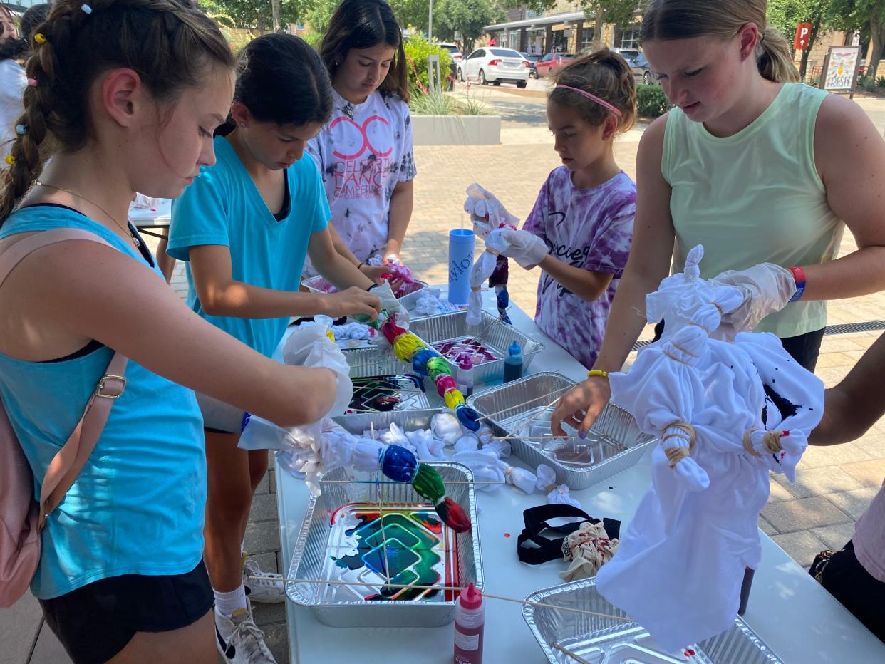 Teens tie-dyed T-shirts and more outside the Bee Cave Public Library.