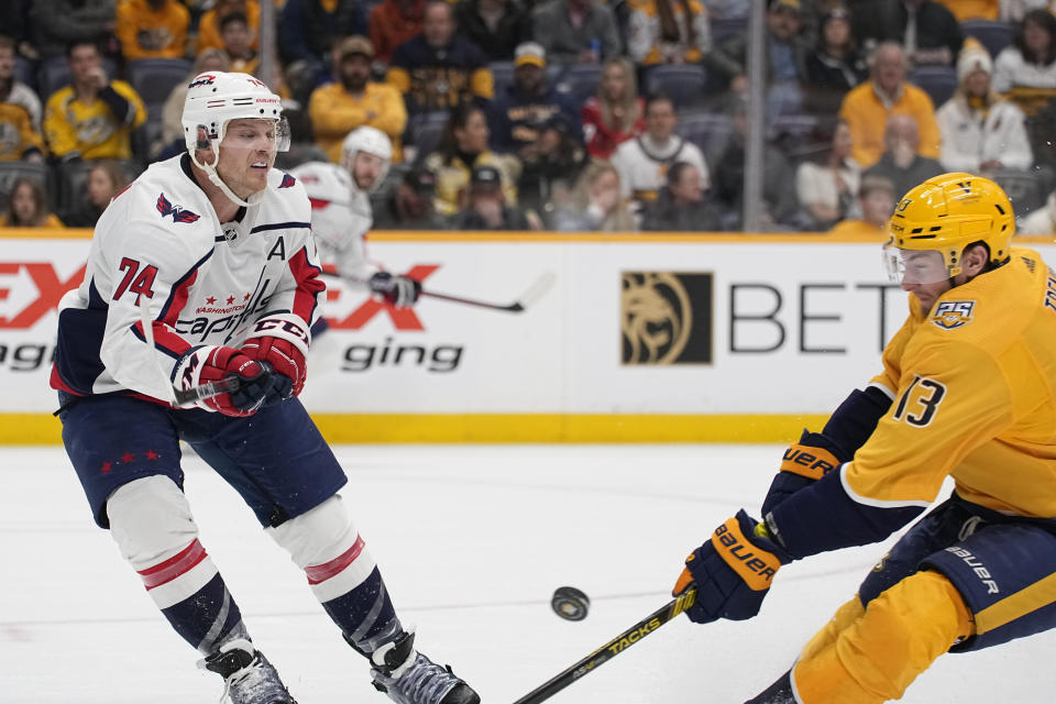 Washington Capitals defenseman John Carlson (74) passes the puck past Nashville Predators center Yakov Trenin (13) during the second period of an NHL hockey game Saturday, Dec. 16, 2023, in Nashville, Tenn. (AP Photo/George Walker IV)