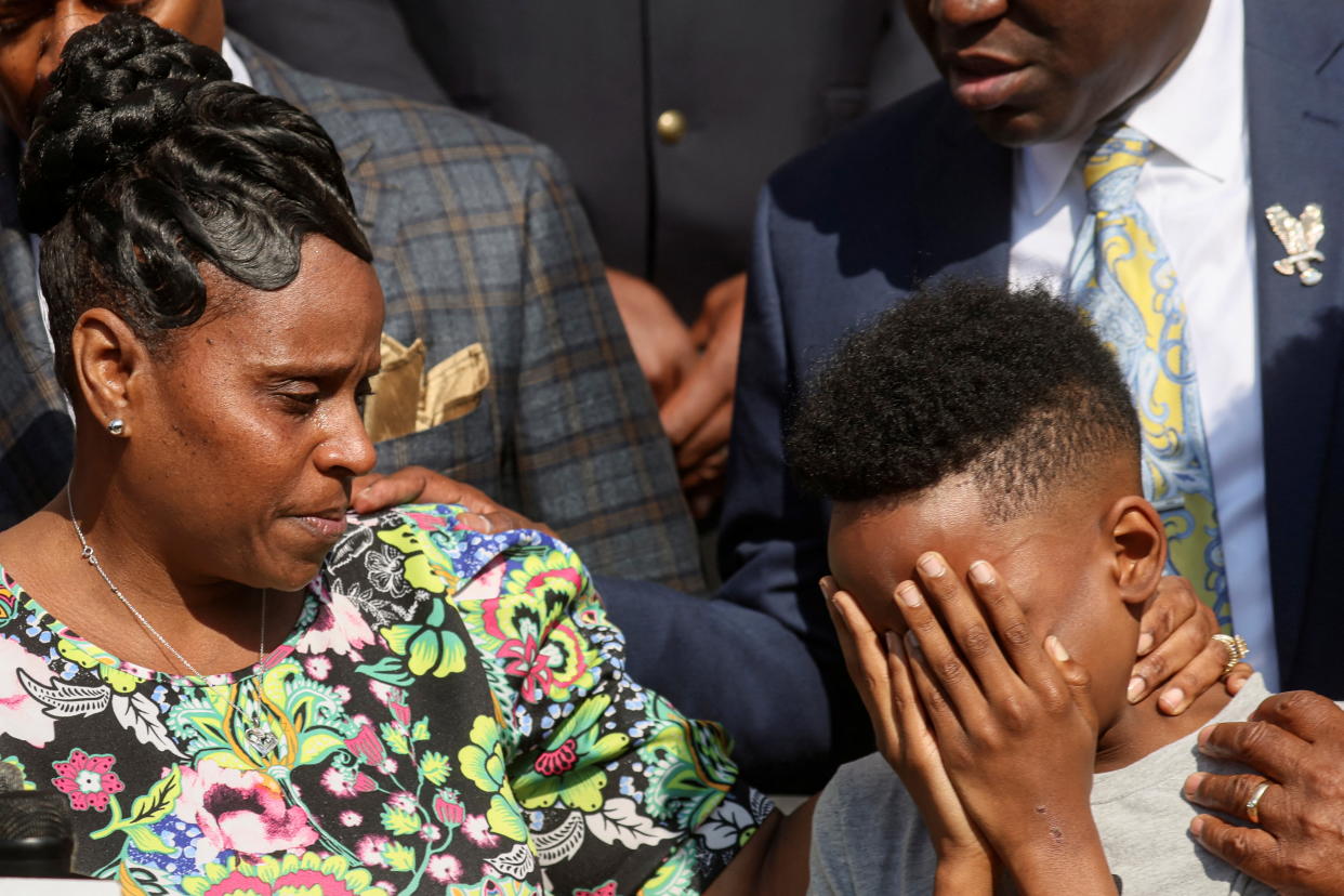 Jacob Patterson, son of shooting victim Heyward Patterson, covers his face with his hands as he stands next to his mother.
