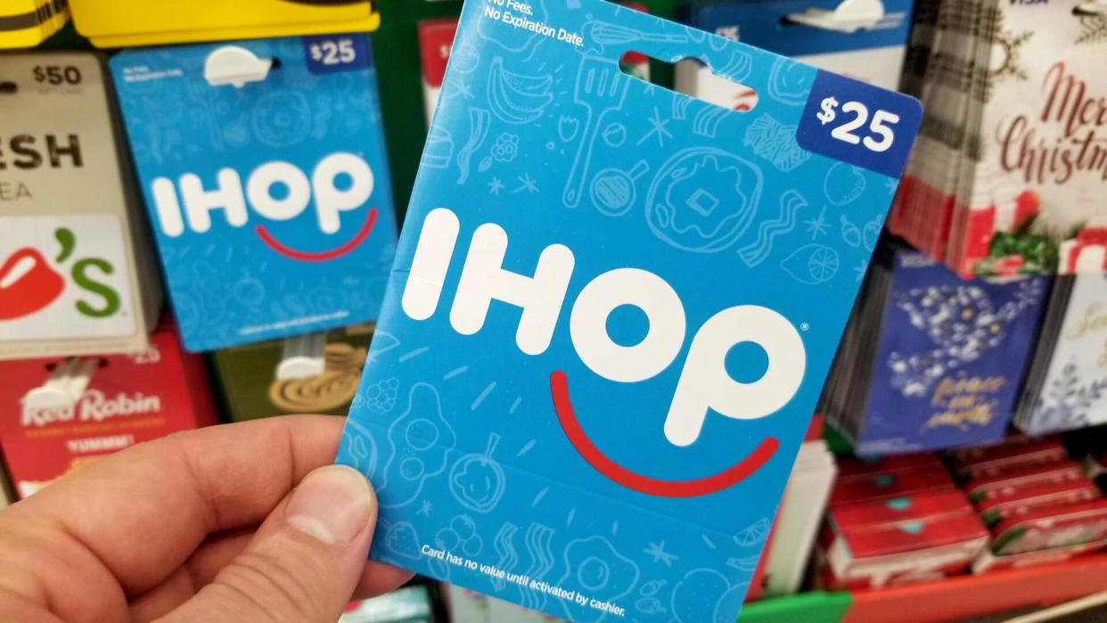 PLATTSBURGH, USA - JANUARY 21, 2019 : IHOP pancake house gift card in a hand over a shelves with different giftcards in a Walmart store.