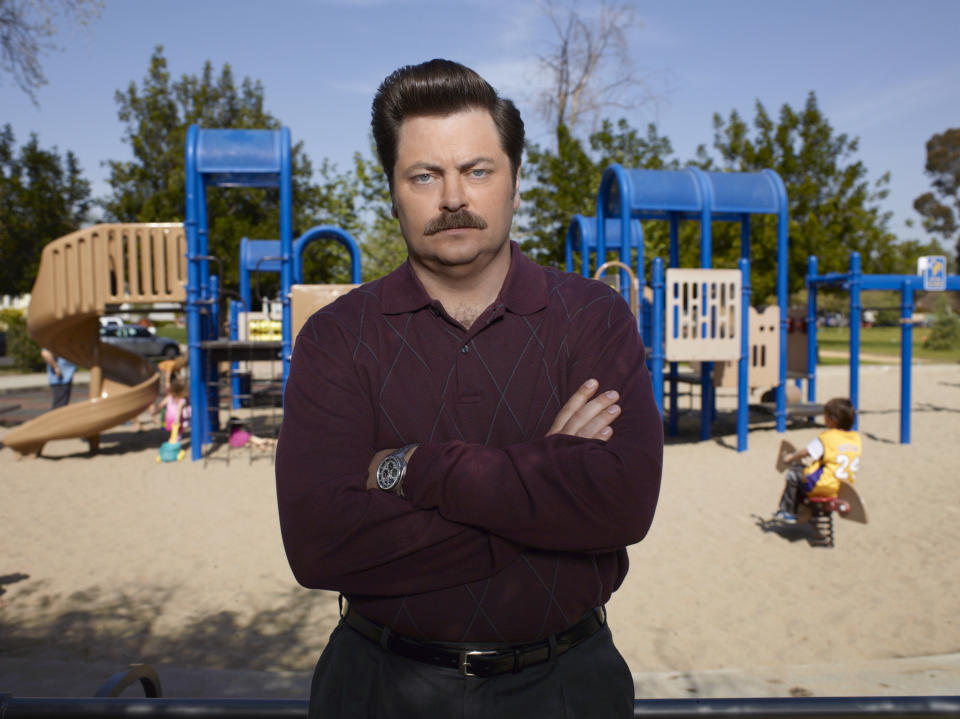 Ron Swanson from "Parks and Recreation" standing in front of a playground