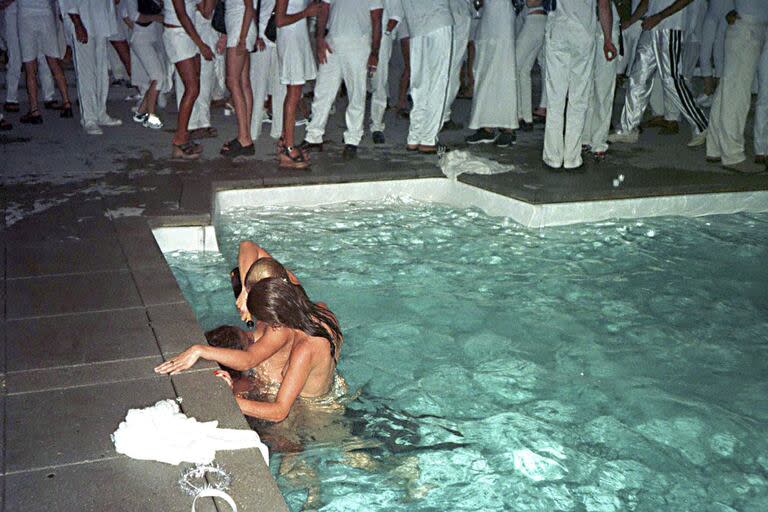 Una postal de la fiesta de 1998: dos chicas semidesnudas abrazan a uno de los invitados de Combs dentro de la pileta mientras le tiran champagne en la boca