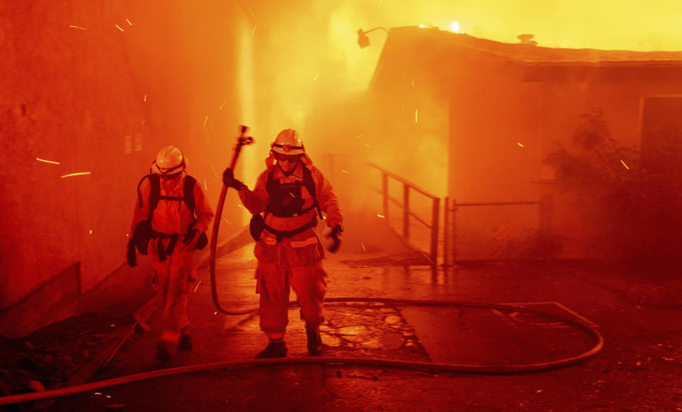 FILE - In this Thursday, Nov. 8, 2018 file photo, firefighters battle the Camp Fire as it tears through Paradise, Calif. A report on firefighter injuries in a deadly Northern California wildfire details harrowing conditions they faced and a few close calls with death. The report released Thursday, Dec. 13, 2018 by the California Department of Forestry and Fire Protection said the Camp Fire overtook three firefighters trying to set a backfire Nov. 8 to stop the blaze. (AP Photo/Noah Berger, File)