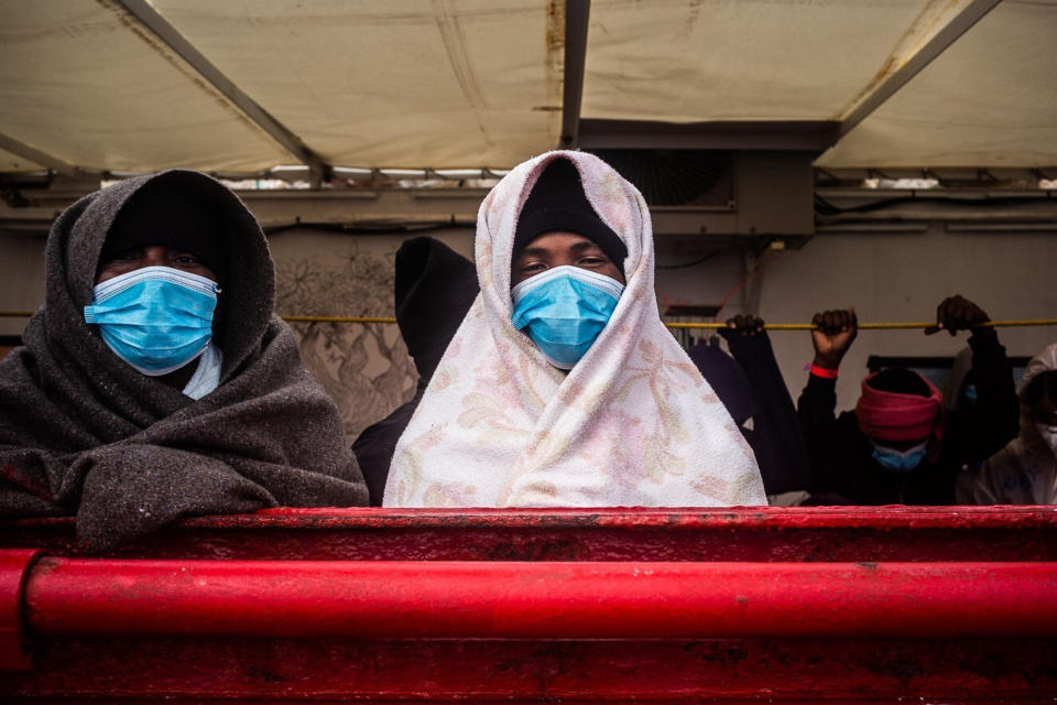 Migrants stand on the deck of the Ocean Viking rescue ship, in the Mediterranean Sea on Sunday, Feb. 7, 2021. A rescue ship with 422 migrants aboard, some of whom tested positive for COVID-19, is heading to Sicily. SOS Mediterranee, the humanitarian group which operates the rescue ship Ocean Viking, told The AP on Sunday that Italy granted the vessel permission to enter the port of Augusta. (Hippolyte/SOS Mediterranee via AP)