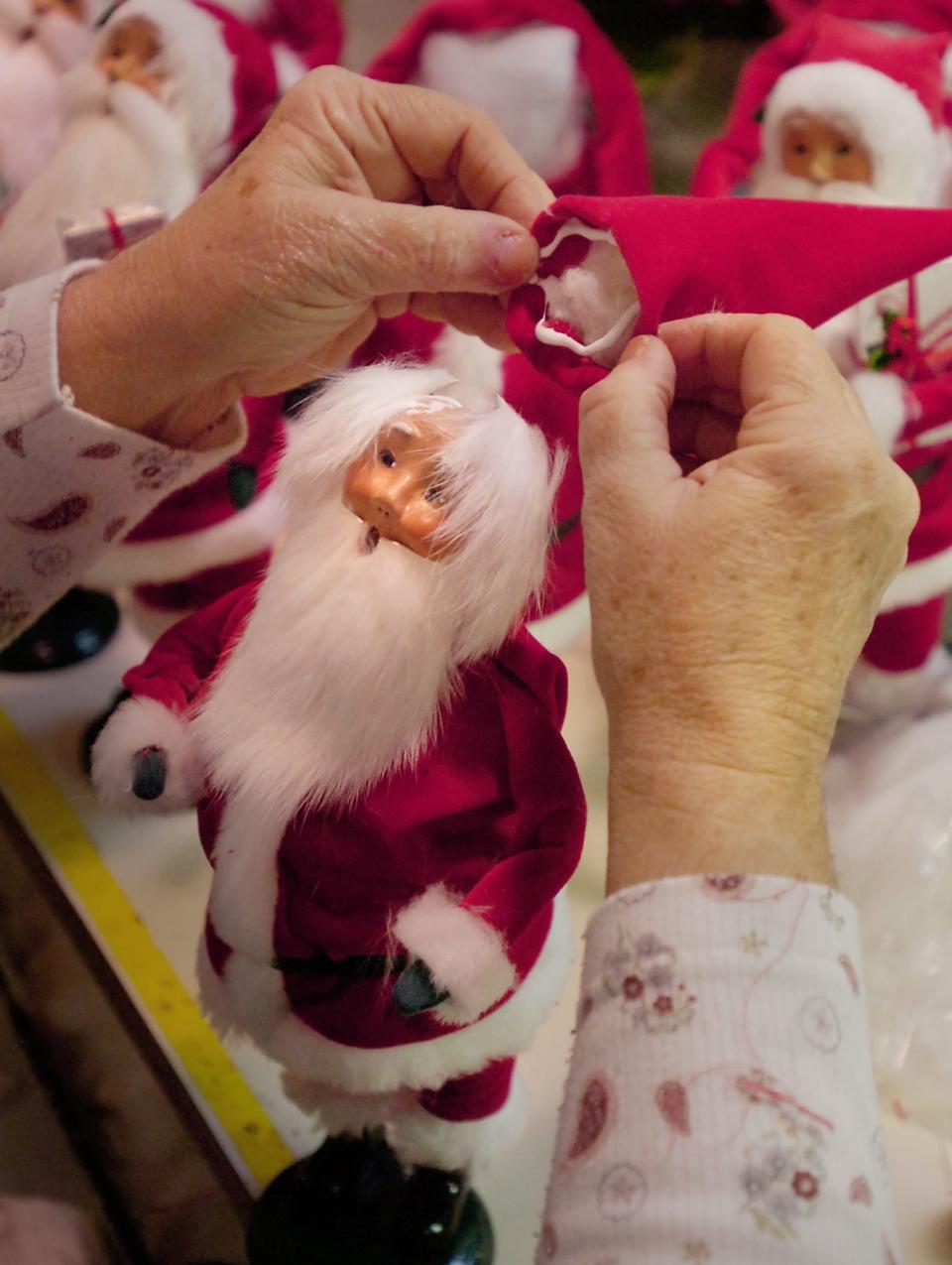 Santa Claus gets a hat during the production of Santa Figures at Byers Choice in New Britain Township.