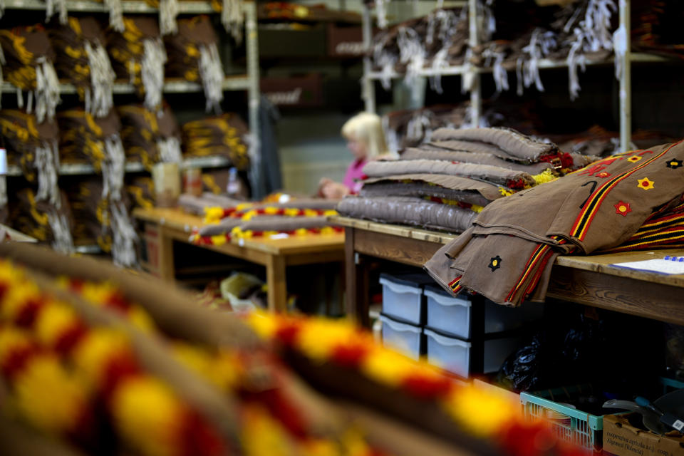 A woman is surrounded by costume elements as she works on details of a Gilles of Binche costume in the Kersten family costume workshop in Binche, Belgium, Wednesday, Feb. 1, 2023. After a COVID-imposed hiatus, artisans are putting finishing touches on elaborate costumes and floats for the renowned Carnival in the Belgian town of Binche, a tradition that brings together young and old and is a welcome moment of celebration after a rough few years. (AP Photo/Virginia Mayo)