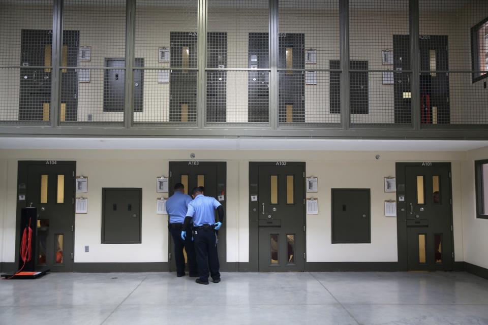 Two guards outside a door on the lower floor of a cellblock