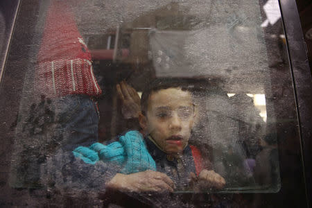 A boy looks through a bus window during evacuation from the besieged town of Douma, Eastern Ghouta, in Damascus, Syria March 22, 2018. REUTERS/Bassam Khabieh