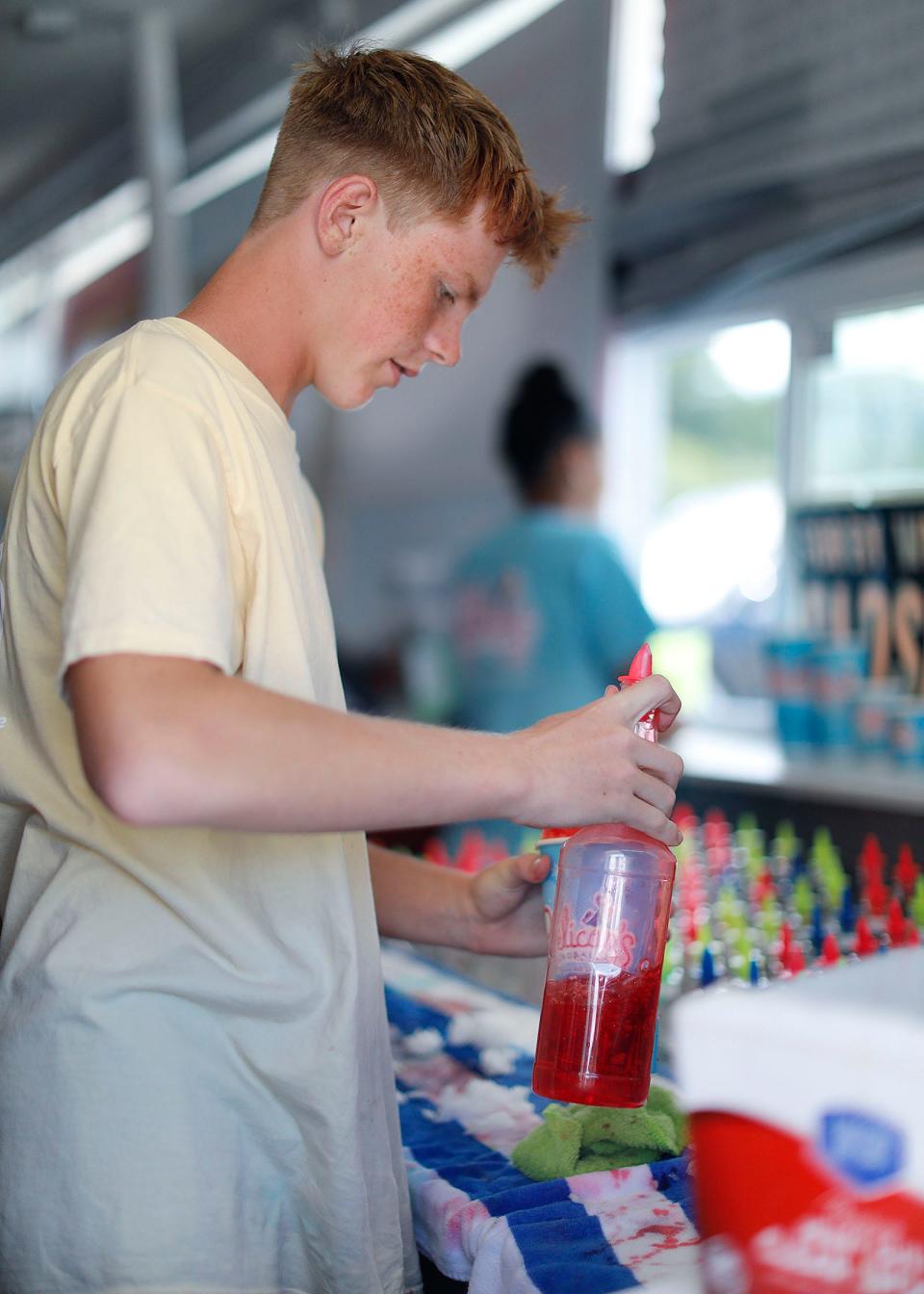 Pelican's employee Conor Walsh, 15, serves SnoBalls at Pelican's in Brant Rock on Thursday, Aug. 18, 2022.