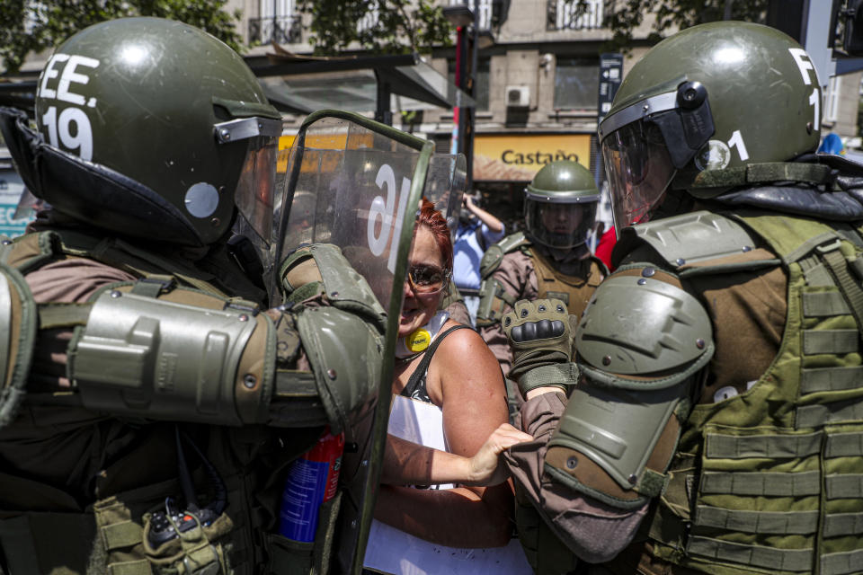 A woman is detained by the police during an anti-government protest in Santiago, Chile, Wednesday, Nov. 6, 2019. Chile's president Sebastian Pinera announced he is sending a bill to Congress that would raise the minimum salary, one of a series of measures to try to contain nearly three weeks of anti-government protests. (AP Photo/Esteban Felix)