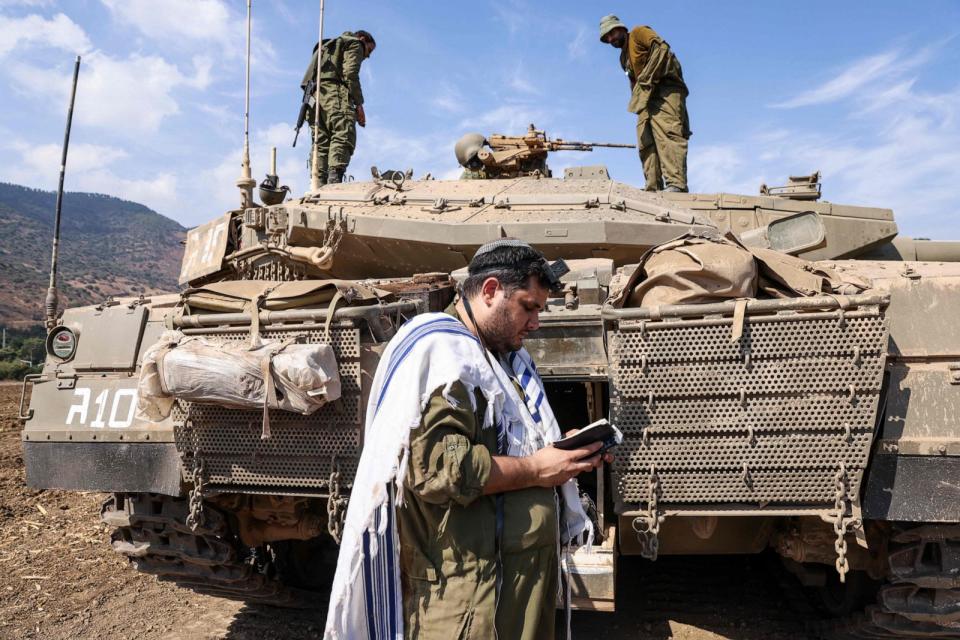 PHOTO: An Israeli sodleir prays standing in front of a Merkava tank on the outskirts of the northern town of Kiryat Shmona near the border with Lebanon on Oct. 8, 2023. (Jalaa Marey/AFP via Getty Images)