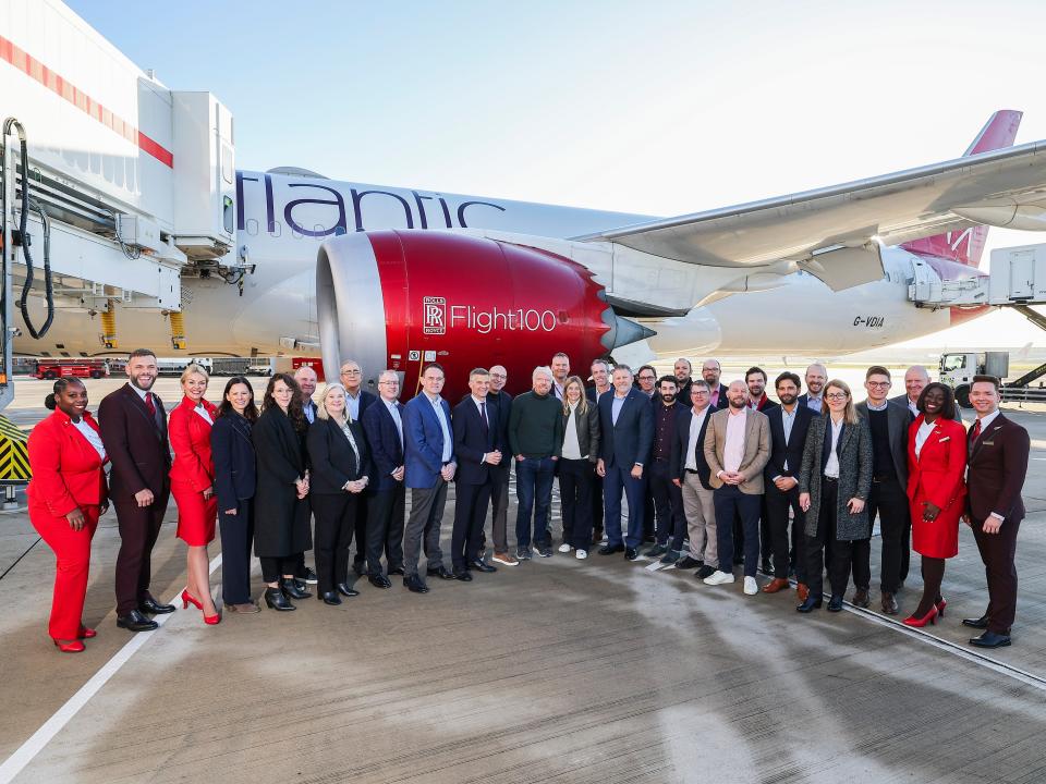 A crowd of Virgin Atlantic staff including Sir Richard Branson pose in front of Virgin Atlantic's Flight 100