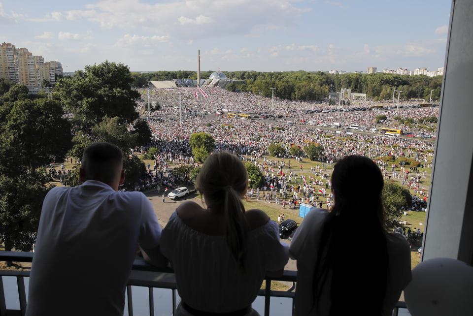 People watch as Belarusian opposition supporters rally in the center of Minsk, Belarus, Sunday, Aug. 16, 2020. Opposition supporters whose protests have convulsed the country for a week aim to hold a major march in the capital of Belarus. Protests began late on Aug. 9 at the closing of presidential elections. (AP Photo/Dmitri Lovetsky)