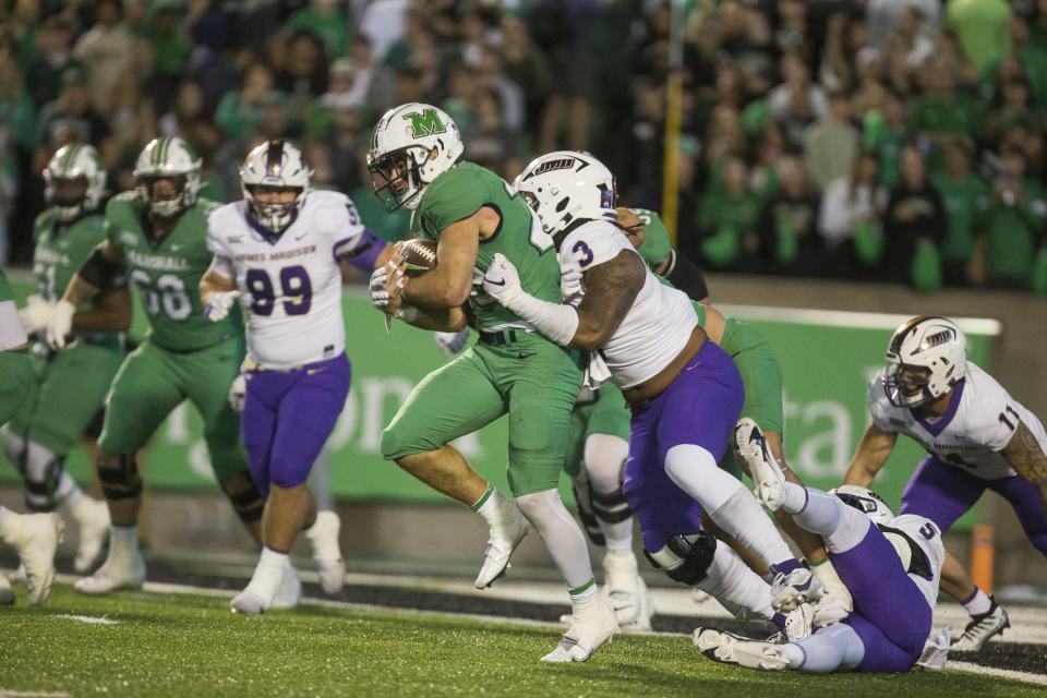 Marshall's Ryan Sissel, center left, takes the ball on a drive as James Madison's Mikail Kamara (3) dives in to tackle him during an NCAA college football game Thursday, Oct. 19, 2023, in Huntigton, W.Va. (Ryan FischerThe Herald-Dispatch via AP)