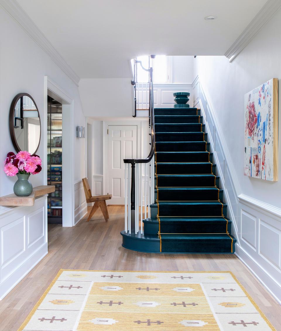 The all-white walls, in Benjamin Moore’s Tundra paint, brighten the entryway. A unique teal staircase with a teal runner, by Summit International Flooring, is a testament to the eccentric yet polished style of the house. The wall-hung console is by FGI Design, and the mirror is by Desiron. The rug is vintage.