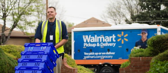 A Wal-Mart worker wheeling a stack of grocery tubs from his truck.