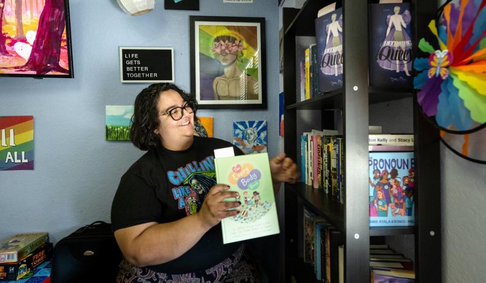 La organizadora comunitaria de MoPride, Verónica Ambrose, muestra la colección de libros para jóvenes adultos en el Central Valley Pride Center, en Modesto, California, el jueves 19 de octubre de 2023.