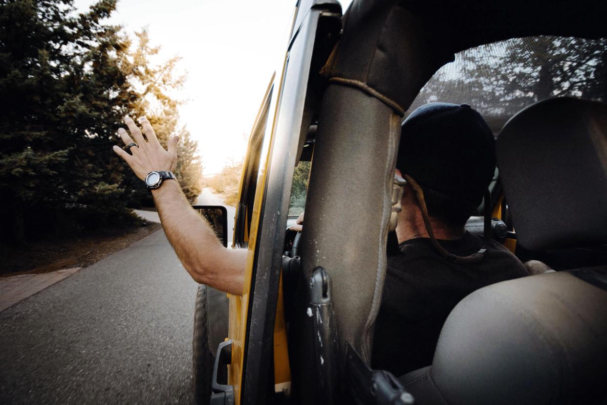 man doing the 'Jeep Wave' to another Jeep