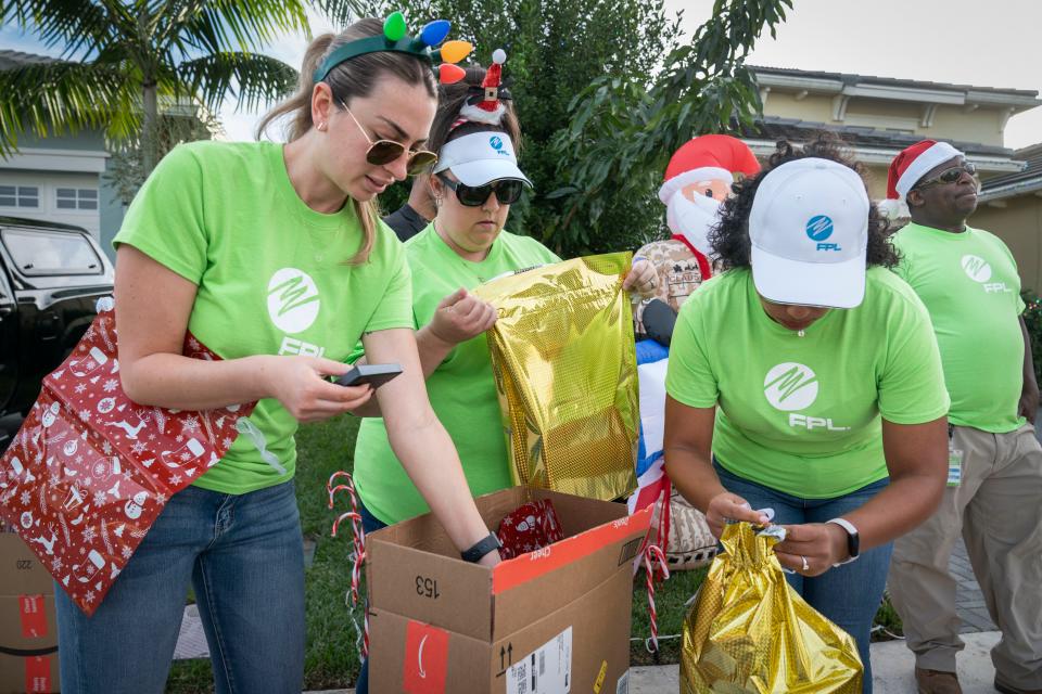 Florida Power & Light Company employees Natalie Fisher, left, Devyn Smith and Amy Kemp wrap gifts for Sandra Antor and her family in Westlake, Florida on December 5, 2023. FPL set up holiday lights and gave gifts to the family in Westlake, Florida on December 5, 2023.