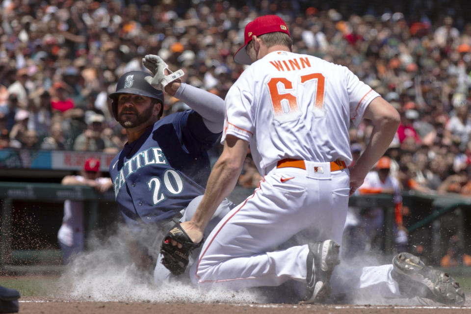 Seattle Mariners' Mike Ford (20) scores from third on a passed ball ahead of the tag by San Francisco Giants starting pitcher Keaton Winn (67) during the second inning of a baseball game, Tuesday, July 4, 2023, in San Francisco. (AP Photo/D. Ross Cameron)