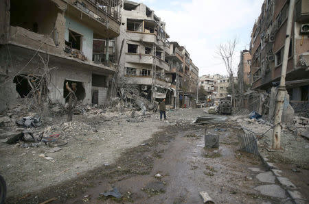 People walk through the damage, after an air raid in the besieged town of Douma, Eastern Ghouta, Damascus, Syria February 23, 2018. REUTERS/Bassam Khabieh