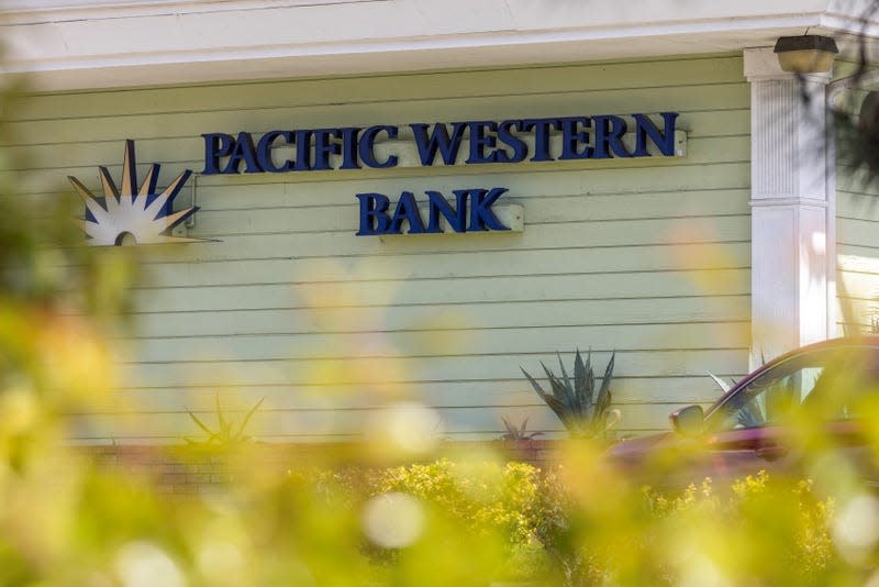 The pistachio-colored exterior of a Pacific Western Bank building, with the sign and logo in navy blue and white on the facade. 