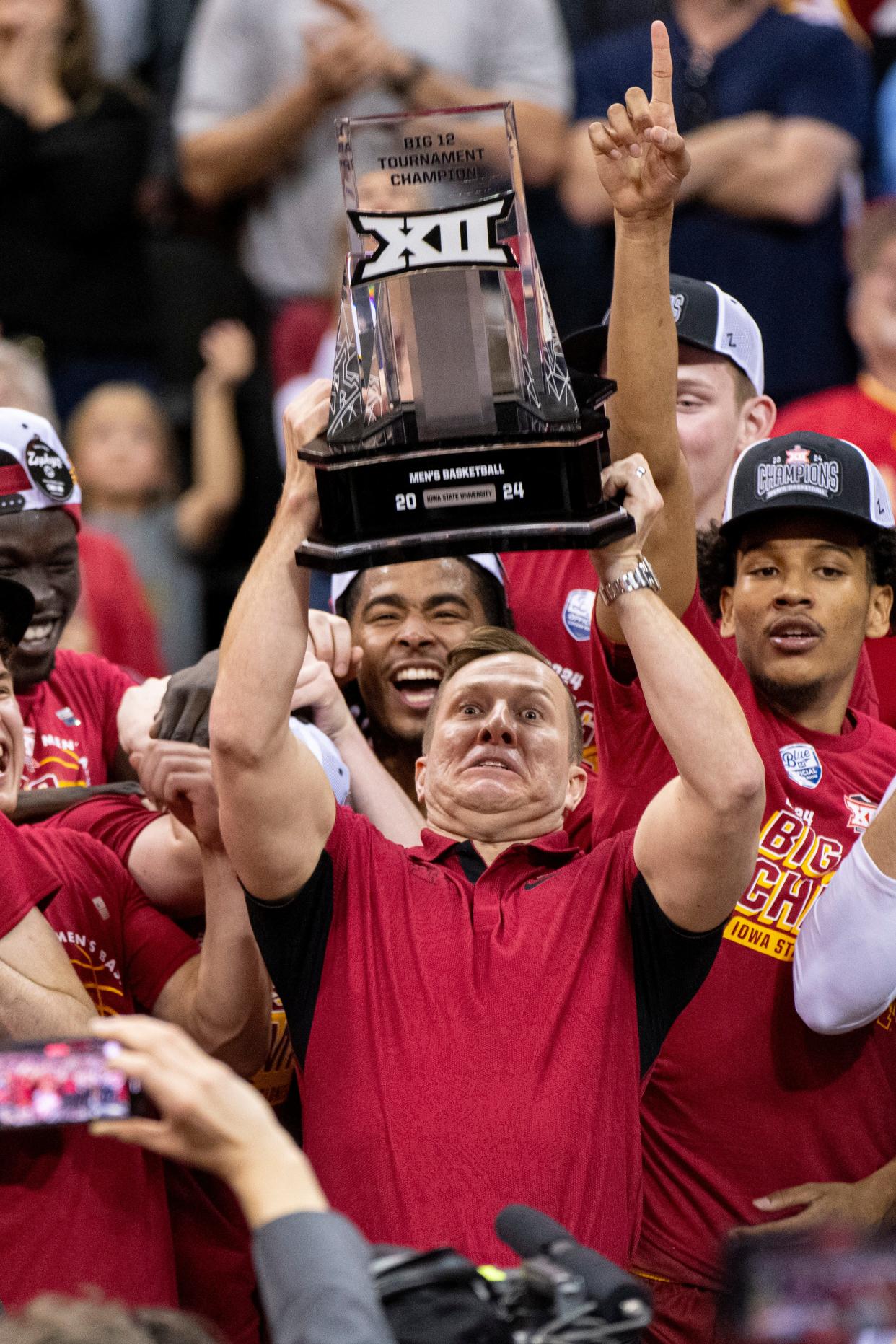 Mar 16, 2024; Kansas City, MO, USA; Iowa State Cyclones head coach TJ Otzelberger hoists the Big 12 Tournament trophy alongside his team after defeating the Houston Cougars at T-Mobile Center. Mandatory Credit: Amy Kontras-USA TODAY Sports