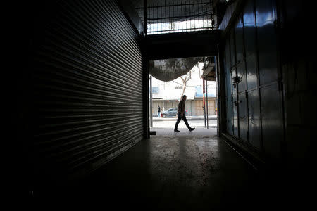 A man passes closed shops as Palestinians call for a general strike, in Hebron, in the occupied West Bank March 31, 2018. REUTERS/Mussa Qawasma