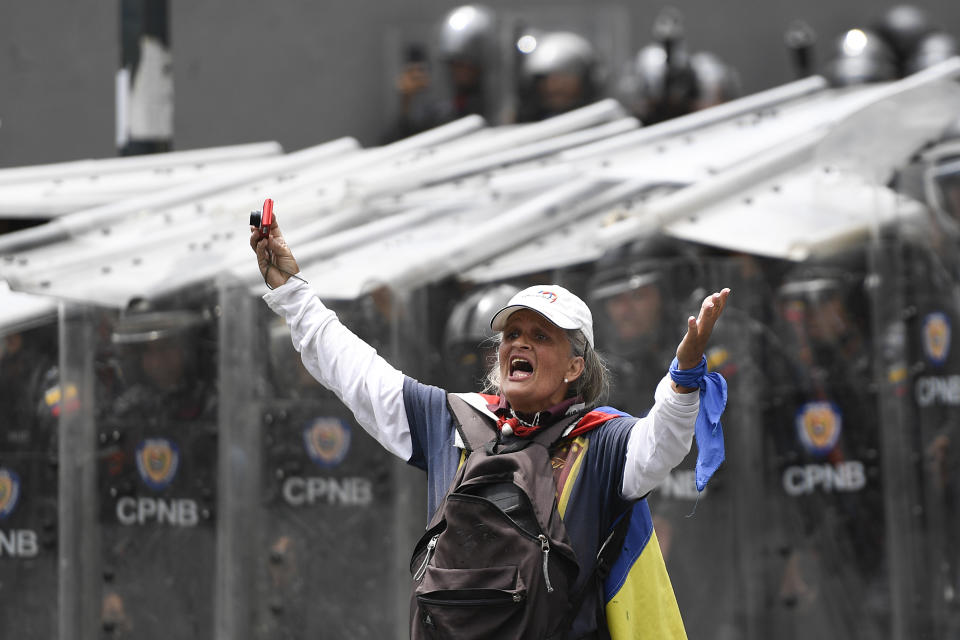 A woman yells in front of a line of police blocking an opposition march in Caracas, Venezuela, Tuesday, March 10, 2020. U.S.-backed Venezuelan political leader Juan Guaido led the march aimed at retaking the National Assembly legislative building, which opposition lawmakers have been blocked from entering. (AP Photo/Matias Delacroix)