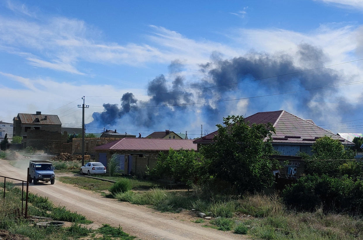 A wall of smoke rises behind a row of houses after the blasts near Novofedorivka.