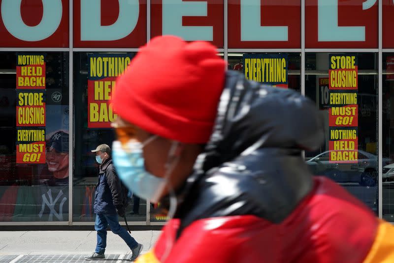 FILE PHOTO: A man wearing a mask rides past a Modell's store that is closed, as retail sales suffer record drop during the outbreak of the coronavirus disease (COVID19) in New York