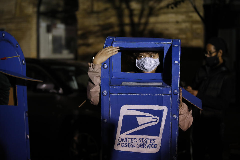 A person wears a costume of a U.S. Postal Service mailbox while demonstrating outside the Pennsylvania Convention Center where votes are being counted, Thursday, Nov. 5, 2020, in Philadelphia, following Tuesday's election. (AP Photo/Rebecca Blackwell)