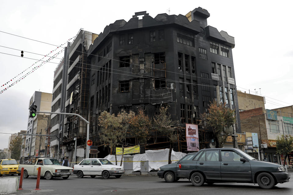 Traffic passes a building set ablaze during recent protests over government-set gasoline prices rises, in Tehran, Iran, Wednesday, Nov. 20, 2019. The demonstrations struck at least 100 cities and towns, spiraling into violence that saw banks, stores and police stations attacked and burned. (AP Photo/Ebrahim Noroozi)