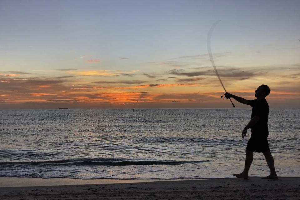 A fisherman casts his line in the early morning hours, Monday, Sept. 19, 2022, on the beach in Surfside, Fla. (AP Photo/Wilfredo Lee)