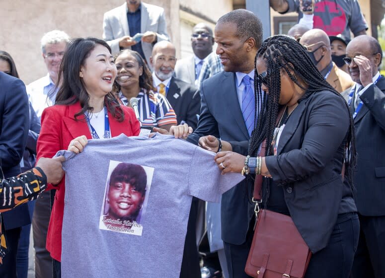 LOS ANGELES, CA-APRIL 29, 2022: Hyepin Im, left, President and Founder of Faith and Community Empowerment, receives a shirt with an image of Latasha Harlins on it from Shinese Harlins-Kilgore, cousin of Latasha Harlins, during a press conference at the intersection of Florence Ave. and Normandie Ave in Los Angeles on the 30th anniversary of the L.A. Riots. (Mel Melcon / Los Angeles Times)