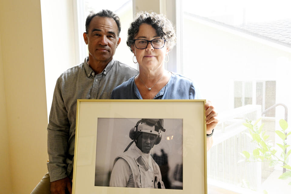 Derek and Suzi Alkonis pose with a photo of their son Lt. Ridge Alkonis on Wednesday, June 1, 2022, in Dana Point, Calif. Their son, a U.S. Navy lieutenant in Japan, faces a potential three-year prison sentence for a car crash that killed two people last year. The sentence has been appealed, and a hearing is set for Wednesday, June 8. (AP Photo/Denis Poroy)