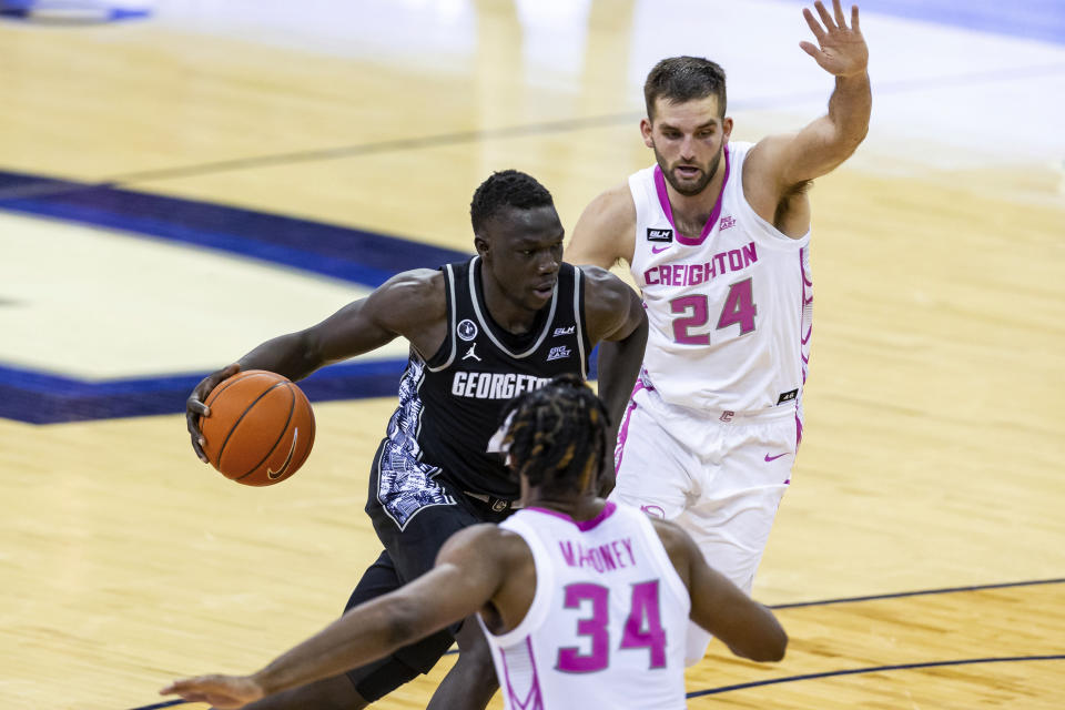 Georgetown forward Chudier Bile (4) drives the basket against Creighton guard Mitch Ballock (24) and guard Denzel Mahoney (34) during the second half of an NCAA college basketball game Wednesday, Feb. 3, 2021, in Omaha, Neb. (AP Photo/John Peterson)