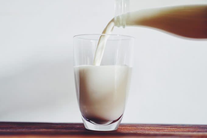 Close-Up Of Bottle Pouring Milk In Glass On Table