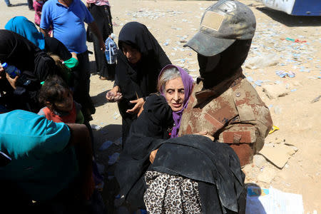 A member of Iraqi Counter Terrorism Service (CTS) forces carries an elderly displaced woman during a battle between Iraqi forces and Islamic State militants in western Mosul, Iraq May 17, 2017. REUTERS/Alaa Al-Marjani