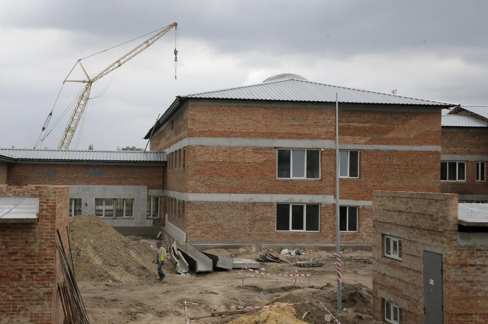 In this photo taken Tuesday, April 29, 2014, a worker walks past a detention center under construction in Zhdanivka, near Donetsk, Ukraine. Moscow calls the detention center under construction near the Russian border a “fascist concentration camp.” Inside the barbed-wire fences, the reality is less ominous: It’s an EU-funded project to hold asylum seekers and illegal immigrants, similar to countless detention centers across Europe. (AP Photo/Efrem Lukatsky)