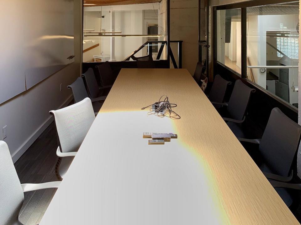 a long meeting table under a wooden ceiling with a skylight