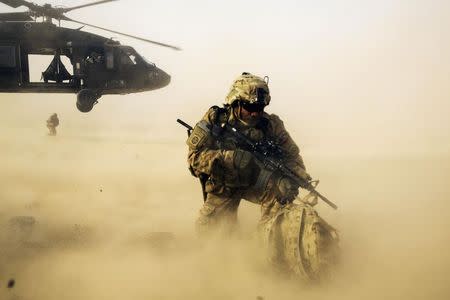 A U.S. soldier from the 3rd Cavalry Regiment shields himself from the rotor wash of a UH-60 Blackhawk helicopter after being dropped off for a mission with the Afghan police near Jalalabad in the Nangarhar province of Afghanistan in this December 20, 2014 file photo. REUTERS/Lucas Jackson/Files
