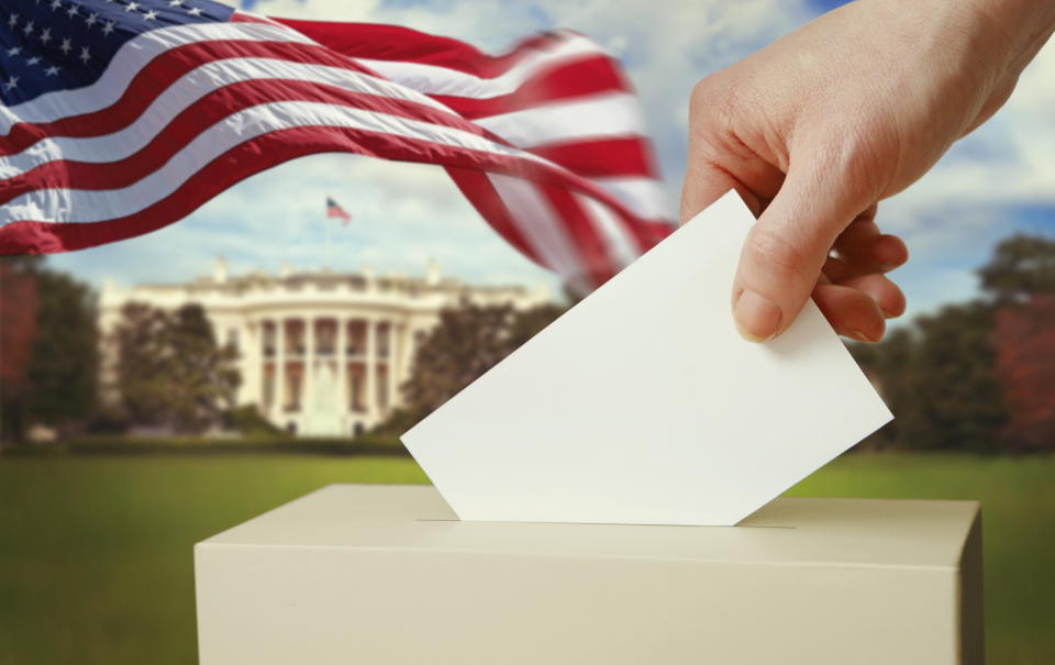 Hand putting a voting ballot into the box with US flag and the White House on the background