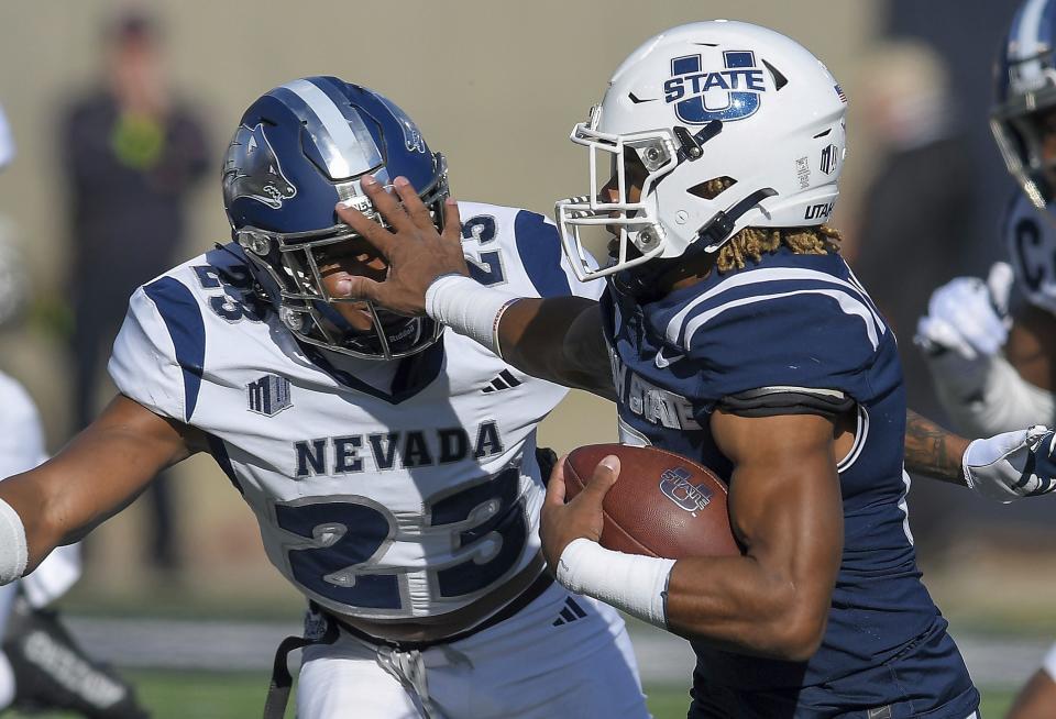 Utah State wide receiver Terrell Vaughn stiff arms Nevada defensive back Richard Toney Jr. (23) during the first half of an NCAA college football game Saturday, Nov. 11, 2023, in Logan, Utah. | Eli Lucero/The Herald Journal via AP